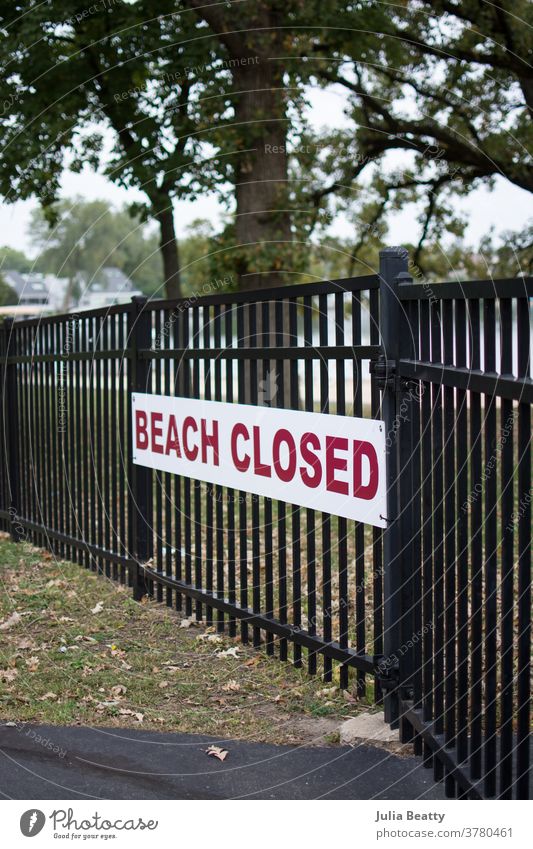 Beach Closed sign on black metal fence beach closed Signs and labeling Signage Warning sign beach closed sign red red letters Caution fall Autumn Autumn leaves