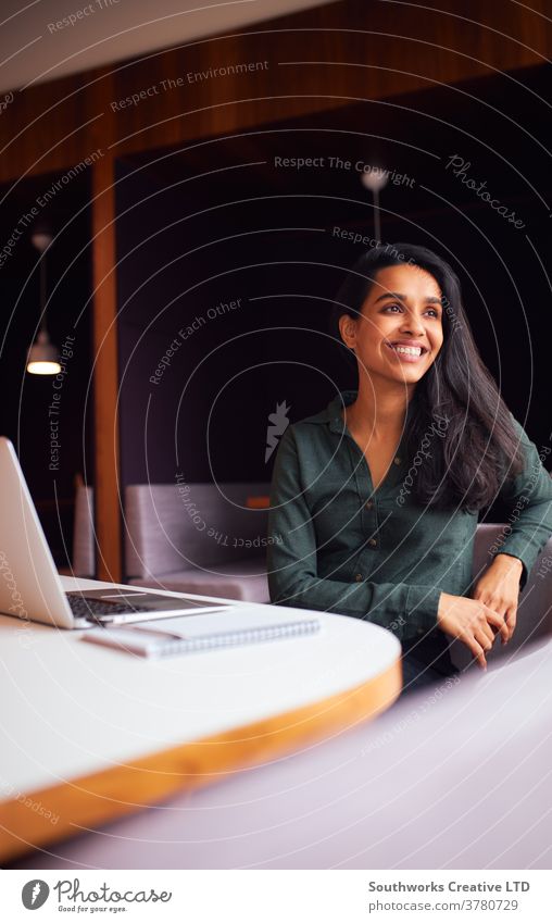 Businesswoman Sitting At Meeting Table Working On Laptop In Modern Open Plan Office business businesswomen meeting office sitting boardroom table laptop
