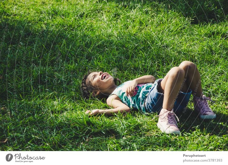 Little girl rests on the grass smiling on a sunny day child lying nature green smile spring kid kids relax field children meadow person flower summer fun young