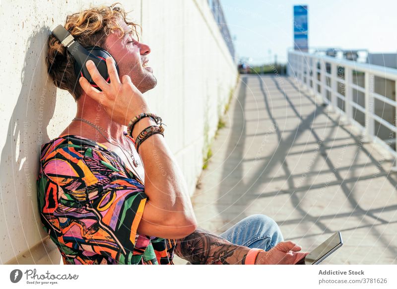 Relaxed male skater listening to music in city man relax enjoy urban trendy hipster headphones skateboard street dreamy eyes closed modern rest cool young guy