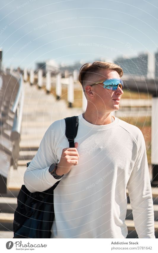 Trendy young female millennial adjusting sunglasses near fence in