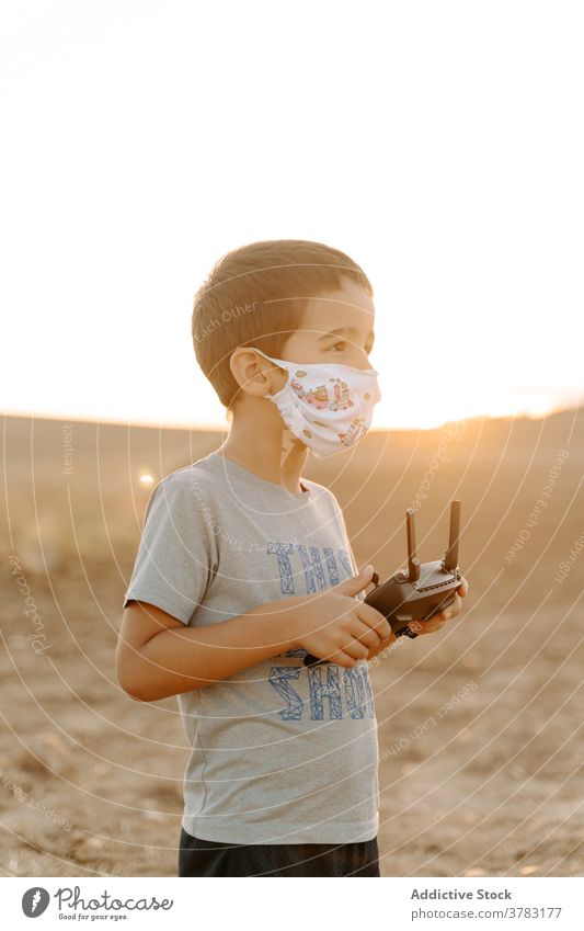 Little kid operating drone in field control remote operate using mask boy play little asian ethnic male child childhood game entertain device uav handset pilot