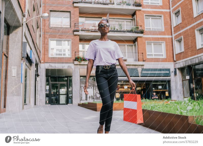 Trendy black woman with shopping bag strolling on street shopper fashion cloth style trendy customer urban young slim female ethnic african american millennial