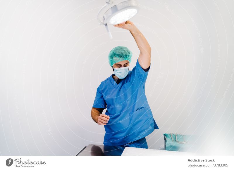 Male veterinarian preparing the lamp for surgery in clinic veterinary operating theater doctor prepare man machine table male uniform mask specialist work job