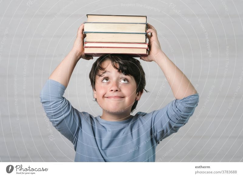 happy child with books on head education wisdom back to school kid childhood intelligence know learn study student think genius schoolboy smile lifestyle