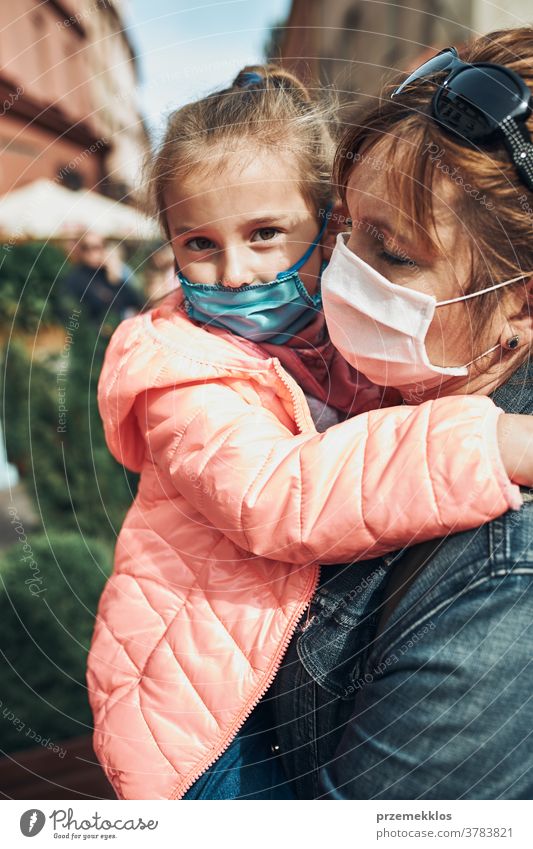 Family mother and her daughter standing in a street downtown wearing the face masks to avoid virus infection call care caucasian chat contagious corona