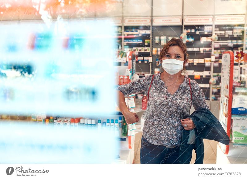 Woman shopping at pharmacy, buying medicines, wearing face mask during pandemic coronavirus outbreak woman chemist covid-19 cover standing town female care