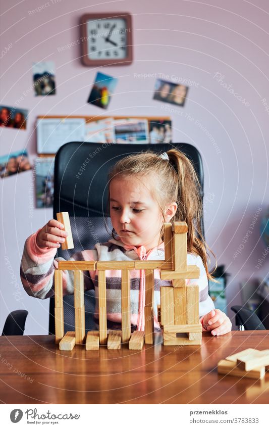 Little girl preschooler playing with wooden blocks toy building a house activity brick child childhood concept construction creativity education fun funny game