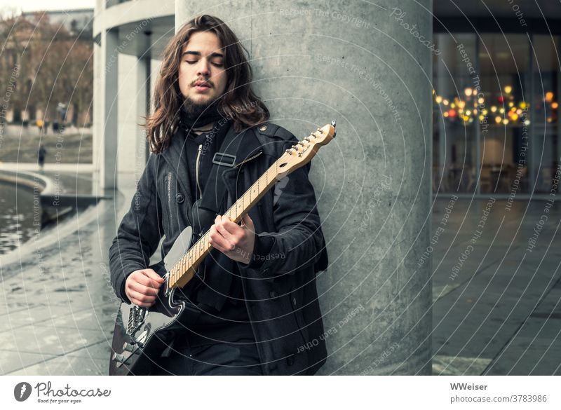 A young musician sings in the government district of Berlin and plucks his guitar Music Musician Guitar Bass guitar Song street music Meditative sad
