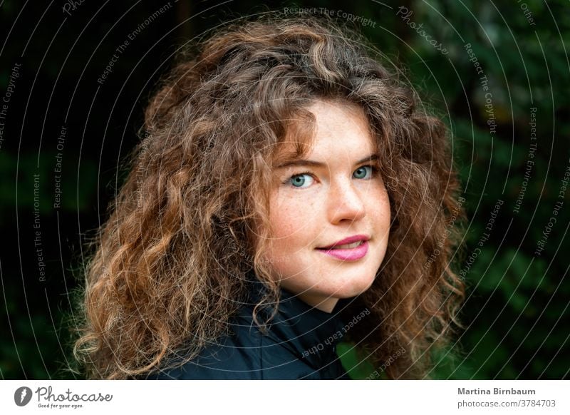 Young natural woman with freckles and wild curly hair looking at the camera young face girl one beautiful caucasian beauty person outdoors hairstyle curls