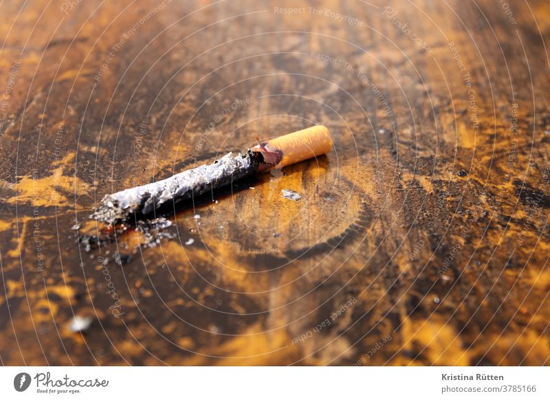 burnt cigarette on wooden table Cigarette tilt cigarette butt Burnt out burnout Completed in the end charred fired with coke burn out Filter cigarette filters