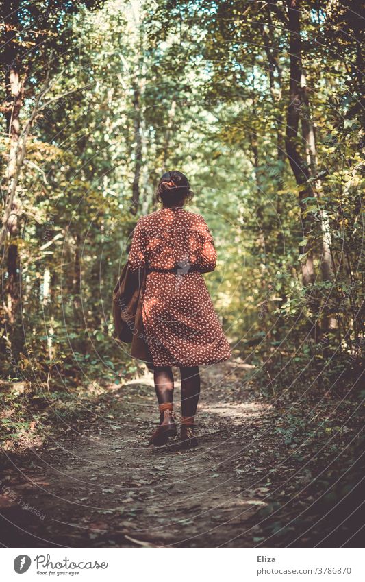 Woman in a red and white patterned dress walks in the forest in autumn. Forest To go for a walk Going Rear view Dress Forest walk Nature by oneself off