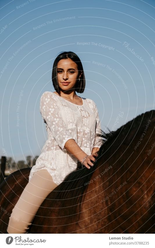 Latin American woman on a brown horse in front of the camera portrait Woman Free air Field Sky Blue Vertical Patagonia Spring Ride Day Animal white shirt