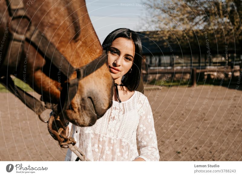 Close-up portrait of a Latina woman touching a horse animal brown team smile active lady rider equestrian elegance suit race background view luxury shirt nature