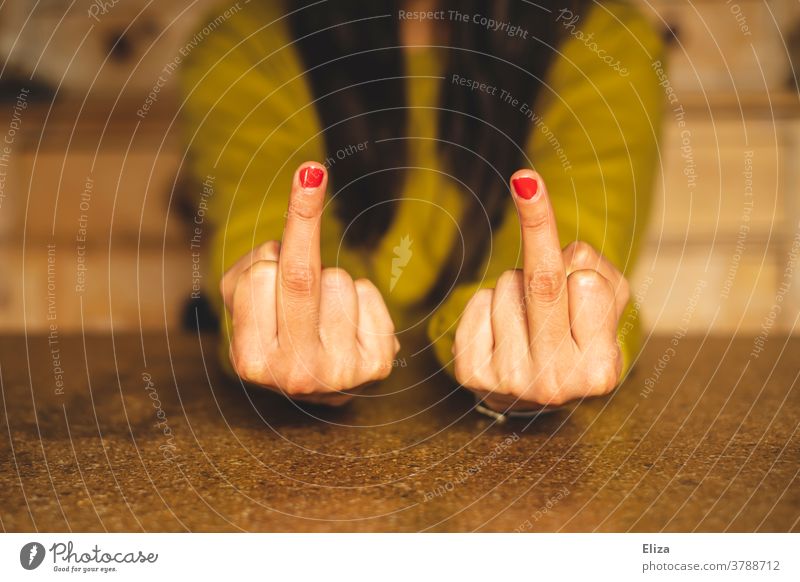 A woman sits at the table and gives the finger with both hands Middle finger Despite Puberty Anger fuck you Give the finger Table Aggravation Aggression