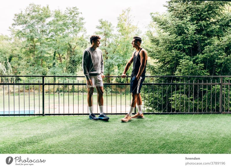 two men dressed in sportswear talk after training at the gym - a