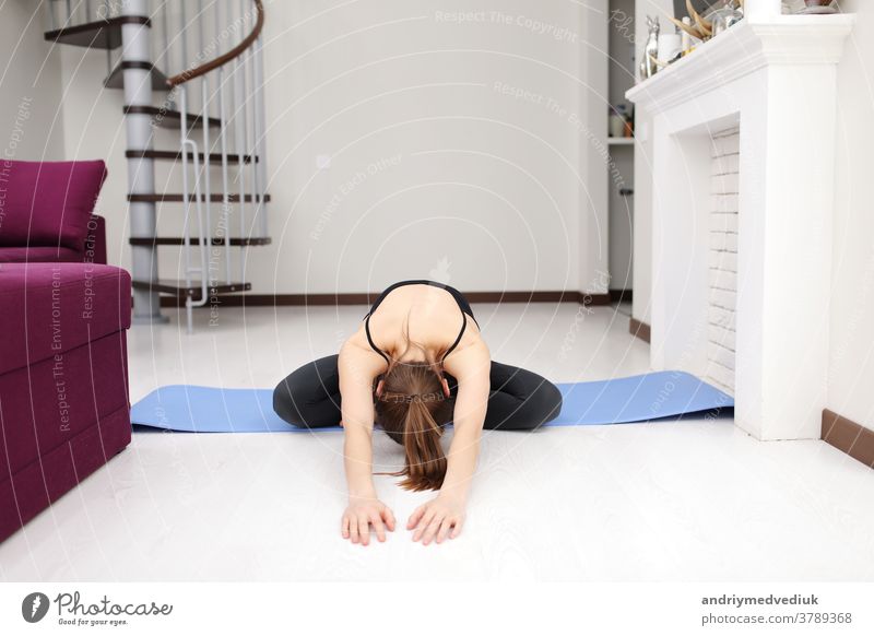 Does yoga exercises on mat on the floor. Young woman with slim body shape in sportswear have fitness day indoors at home. young girl stretch modern occupation