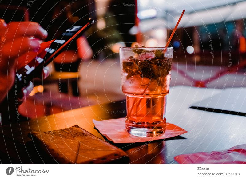 Junge Frau mit Smartphone und Cocktail in einer Bar gardasee urlaub drink cocktail getränk ausgehen alkohol trinken smartphone warten verabredet