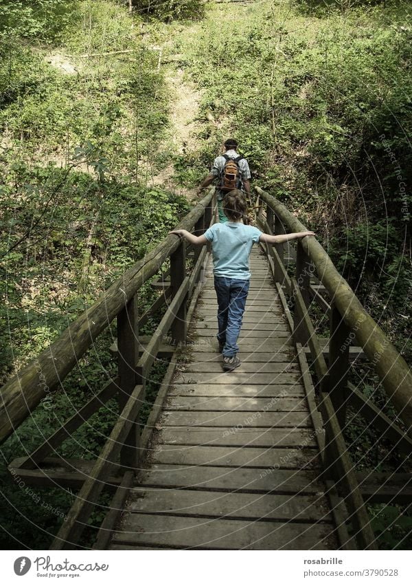 spaces | child walks behind father over a wooden bridge Wooden bridge Child Father Bridge ensue Trust To hold on Going Hiking stroll togetherness