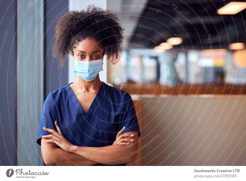 Female Doctor In Face Mask Wearing Scrubs Under Pressure In Busy Hospital During Health Pandemic doctor nurse scrubs key worker female woman wearing face mask