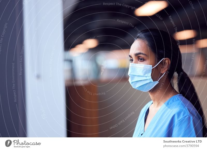 Female Doctor In Face Mask Wearing Scrubs Under Pressure In Busy Hospital During Health Pandemic doctor nurse scrubs key worker female woman wearing face mask