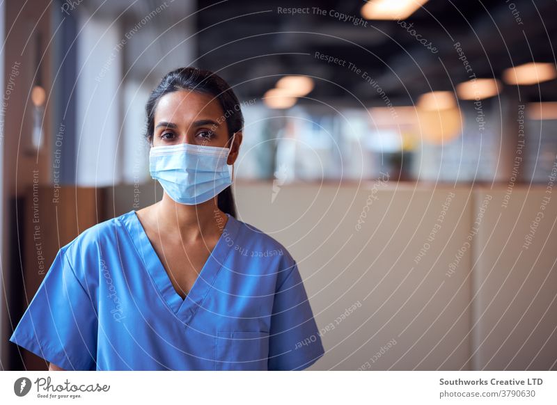 Female Doctor In Face Mask Wearing Scrubs Under Pressure In Busy Hospital During Health Pandemic doctor nurse scrubs key worker female woman wearing face mask