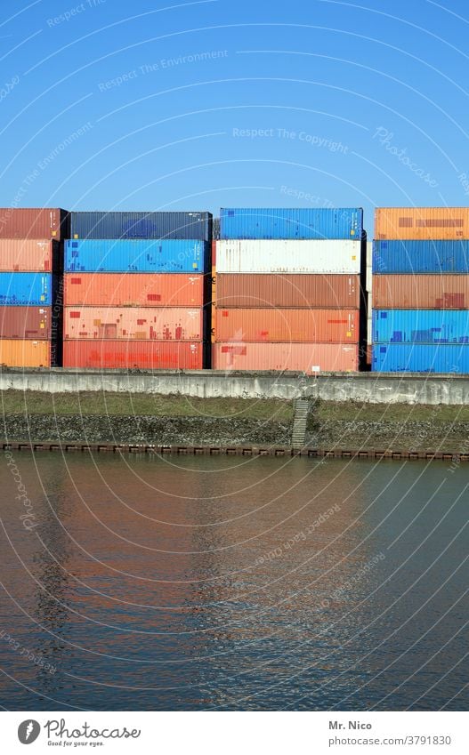 Stacked containers in the port Container Harbour Container terminal Logistics Port City Container cargo Trade Navigation Economy Water Blue sky pile Reflection