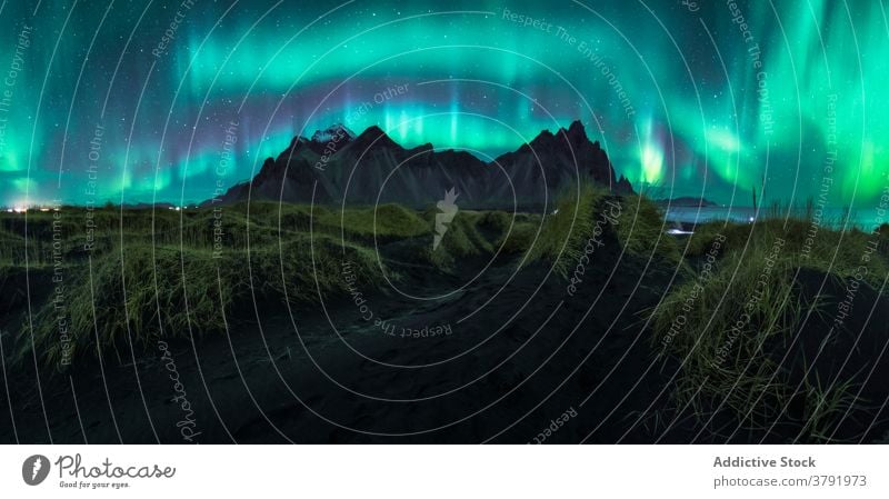 Northern lights over mountains at night northern aurora borealis scenic illuminate highland sky iceland color terrain dark rocky scenery picturesque environment