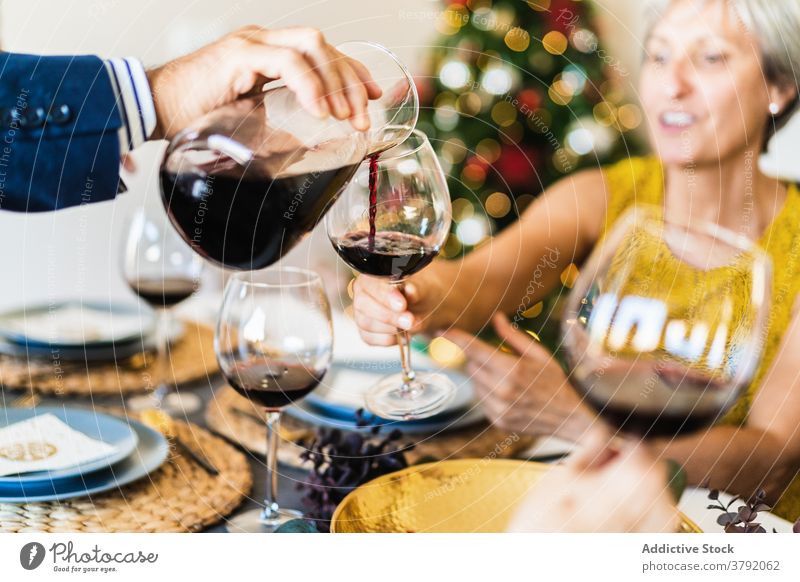 Man serving wine on Christmas eve xmas cheers wineglass christmas toast faceless celebrate gather crop view friend cheerful festive alcohol positive winter