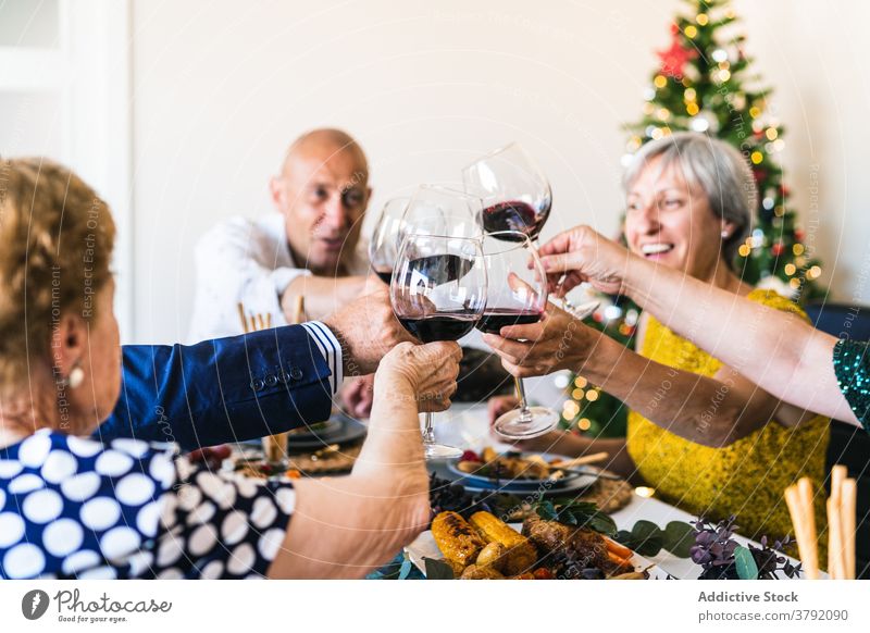 Cheerful friends with red wine during Christmas celebration at home cheers glass celebrate happy christmas food festive dinner gather table alcohol drink