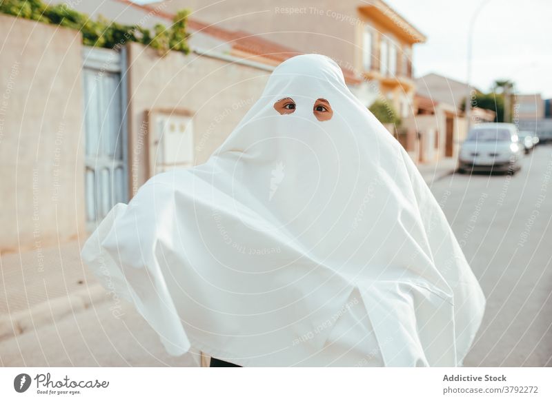Spooky child in ghost costume in city halloween holiday kid having fun spooky scare frighten street tradition childhood season autumn fall celebrate scary