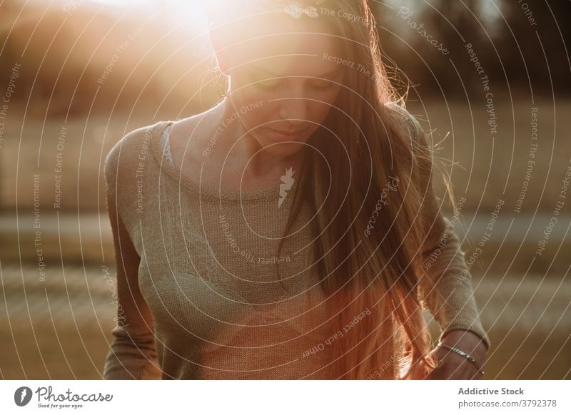 Crop calm attractive woman standing in nature in evening sun charming serene peaceful tranquil gorgeous unemotional park sunbeam gentle tender sensitive trendy