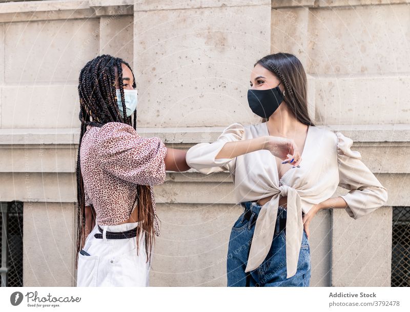 Girlfriends in protective masks greeting each other with elbow bump coronavirus women safety covid covid 19 covid19 female young multiracial multiethnic diverse