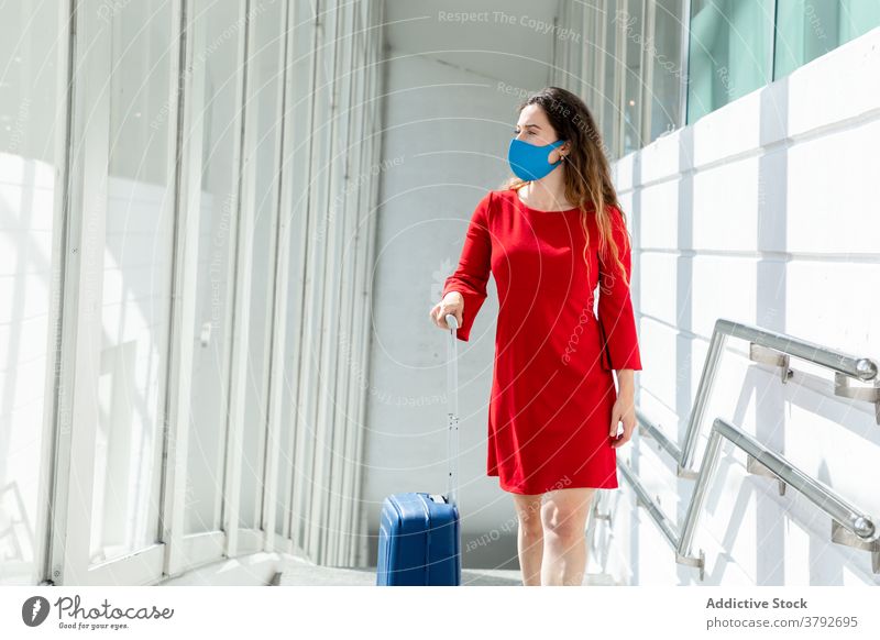 Traveling woman with baggage in airport travel wait flight departure suitcase mask coronavirus female tourist passenger vacation holiday window trip journey
