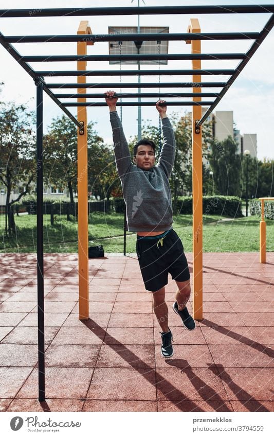 Young man bodybuilder exercising on monkey bars during his workout in a modern calisthenics park care caucasian health lifestyle male one outdoors person sport