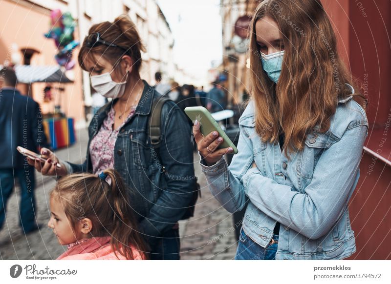 Young women using smartphones standing in a street downtown wearing the face masks to avoid virus infection call care caucasian chat contagious corona
