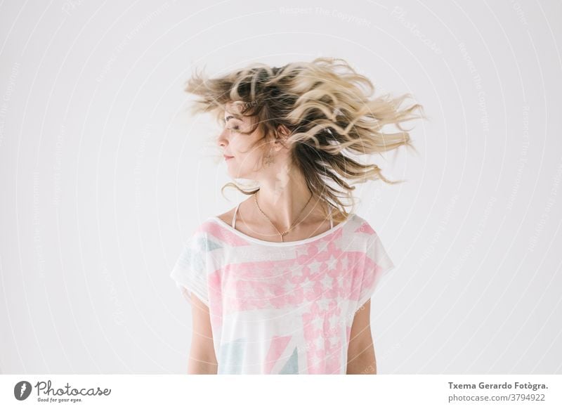Natural portrait of blonde girl shaking her hair on white background natural motion shake shirt unfiltered expression european caucasian woman young adult