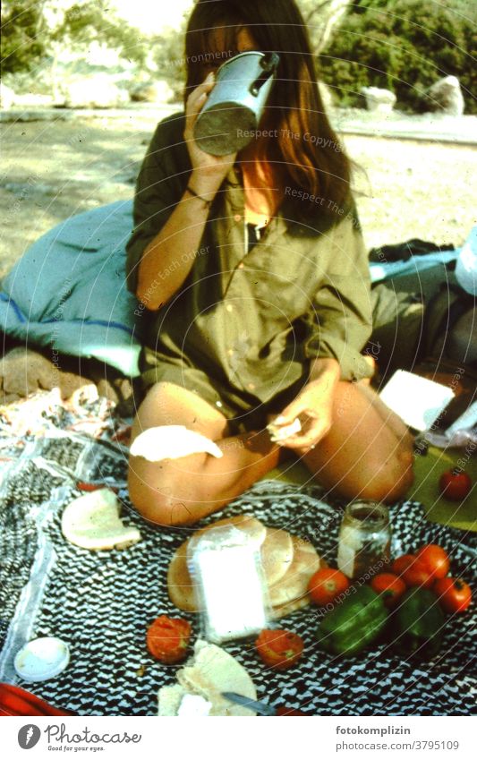 woman sitting on the ground with a picnic Picnic picnic blanket drinking globetrotter traveling camping simple simple living outside outdoor outdoors trip food