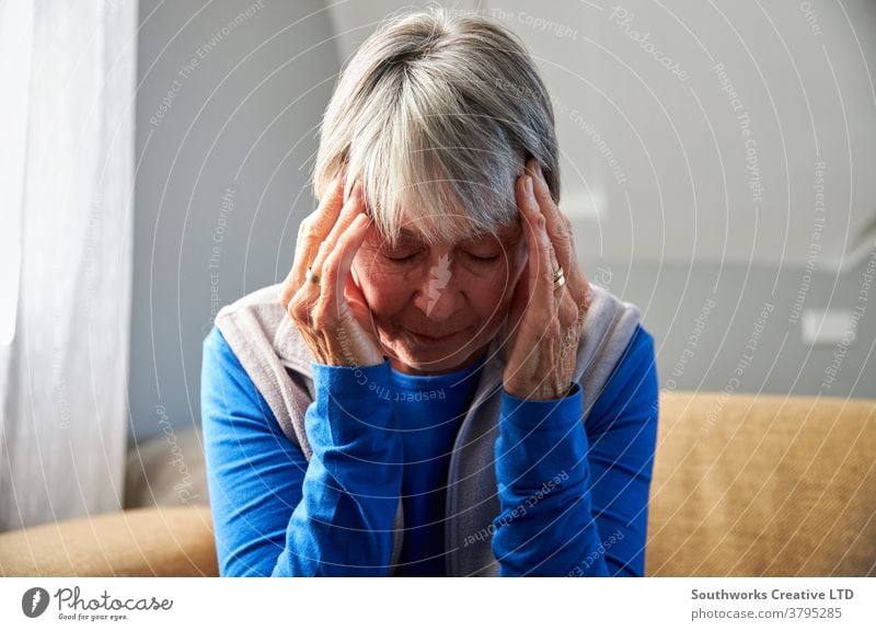 Senior Woman Suffering With Stress Or Headache At Home Holding Head In Pain senior seniors woman at home headache migraine health pain holding stress stressed