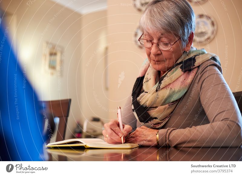 Happy athletic senior woman in sportswear sitting on yoga mat at home and  using modern cellphone Stock Photo