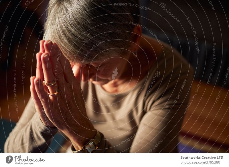 Close Up Of Senior Woman At Home Praying Or Meditating With Hands Together senior woman praying religious prayer seniors at home religion faith belief