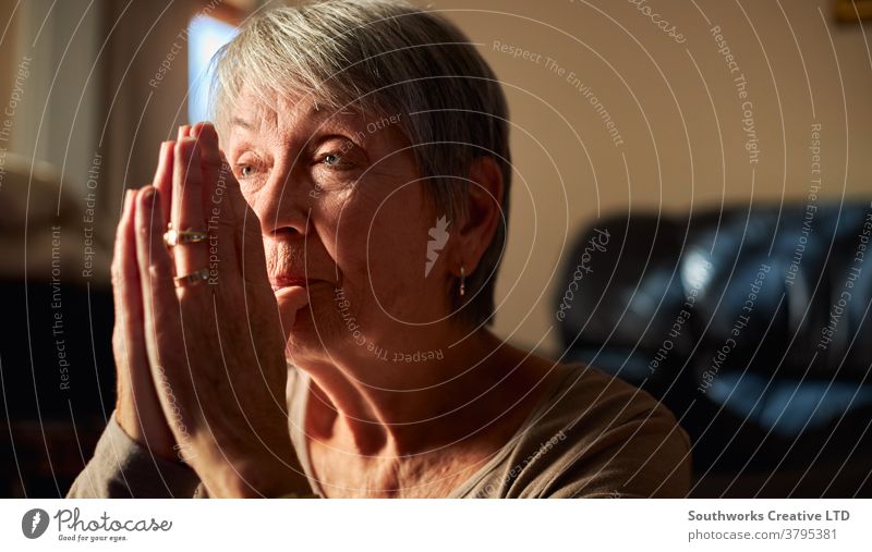 Close Up Of Senior Woman At Home Praying Or Meditating With Hands Together senior woman praying prayer religious faith seniors at home religion belief