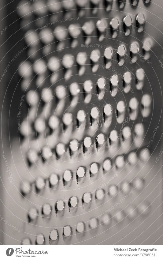 detailed monocrome macro shot of a metal cheese grater blade cook rectangular cooking diet kitchen over rub shiny chef retro cuisine abstract food sharp