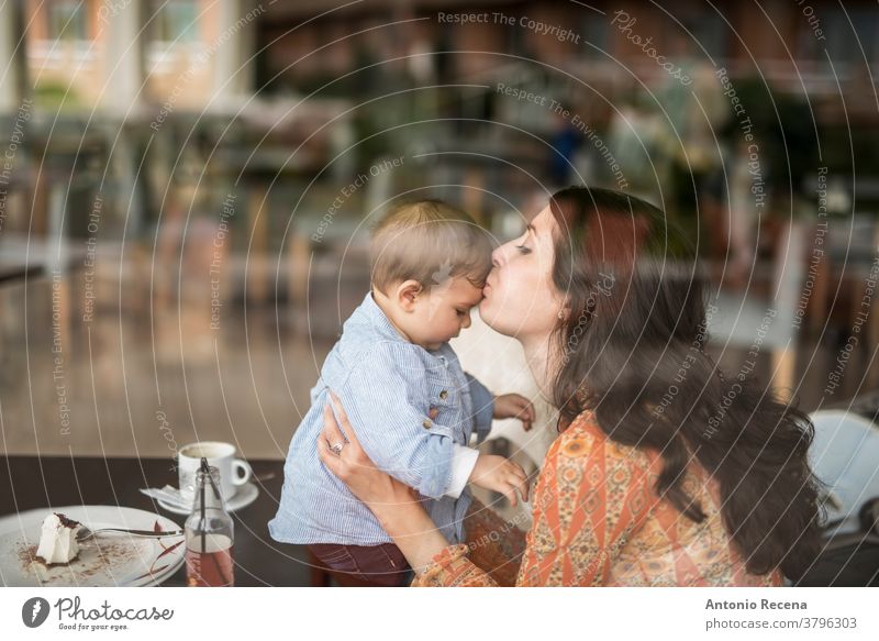 mother kissing little baby at bar mother's day son restaurant love lifestyles people women woman kid child children boy care parent mothers day spanish