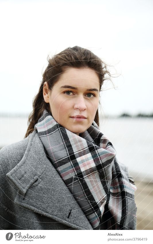 Close portrait of a young woman on the beach of the Elbe Woman Young woman 18-25 years warmly pretty Charming Slim Brunette long hairs Fresh Large smart