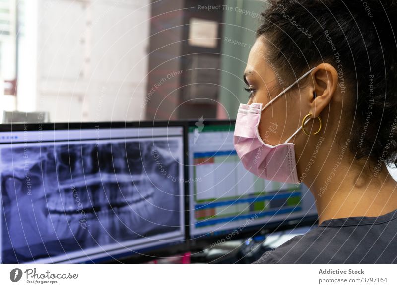 Ethnic dentist in mask examining X ray in hospital x ray examine dental teeth woman doctor stomatology monitor computer female ethnic black african american