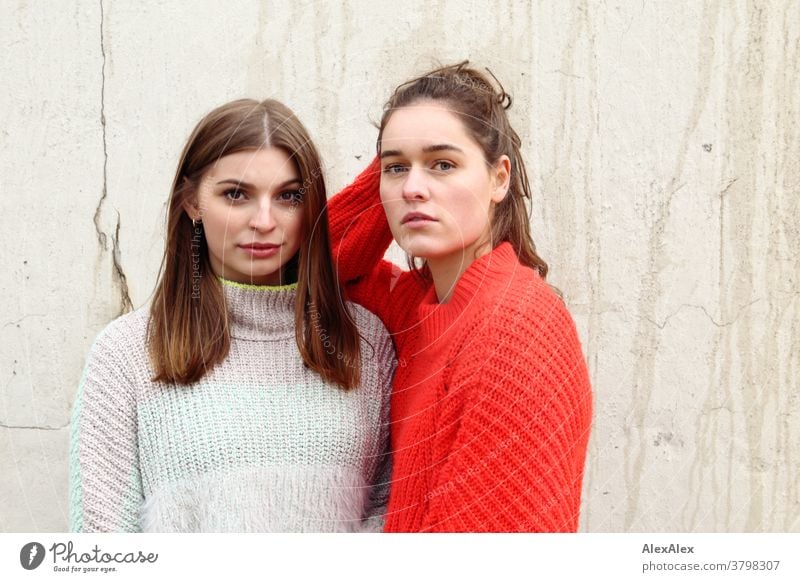 Portrait of two young women - friends - in front of a concrete wall Woman Young woman 18-25 years warmly pretty Charming Slim Brunette long hairs Fresh Large