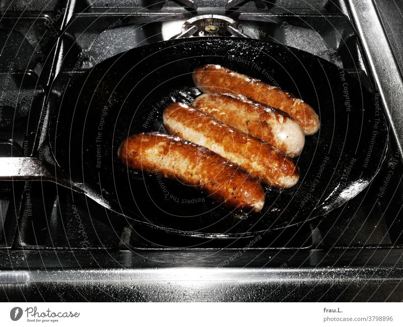 Browned organic sausages sizzle together almost enthusiastically. boil Kitchen Cooking hob High-grade steel Pan iron pan Fat greasily Gas stove Stove