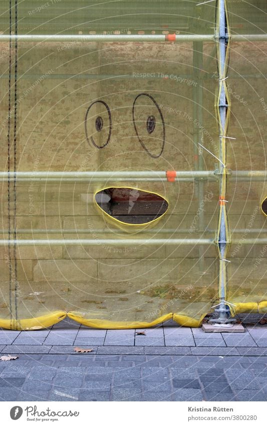safety net on scaffolding with painted eyes and mouth opening Mouth Face Open Amazed cheerful joyfully Expression facial expression Painted painted on ripped