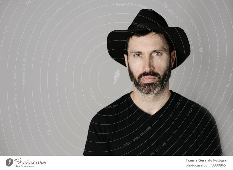 Close-up portrait of a handsome bearded middle-aged man with hat against neutral background studio confident grey guy face isolated adult lifestyle cool indoors